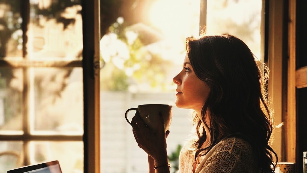 Woman by a morning window with coffee — a quiet moment of intentional rest