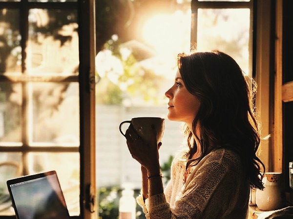 Woman by a morning window with coffee — a quiet moment of intentional rest