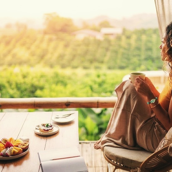 Woman relaxing on a terrace overlooking lush nature